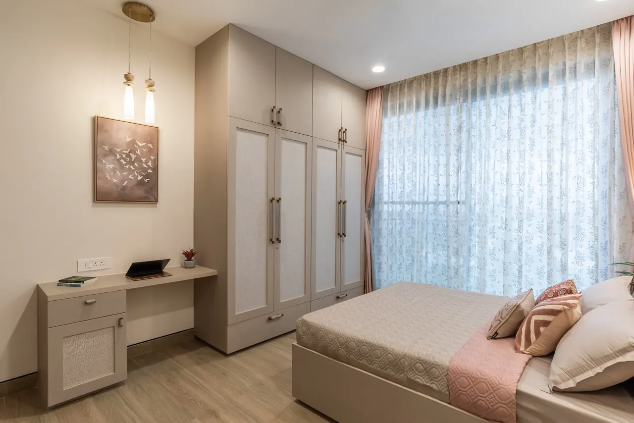 Bedroom with a beige wardrobe with textured panels, a wall-hung desk, a bird artwork and floral sheer curtains