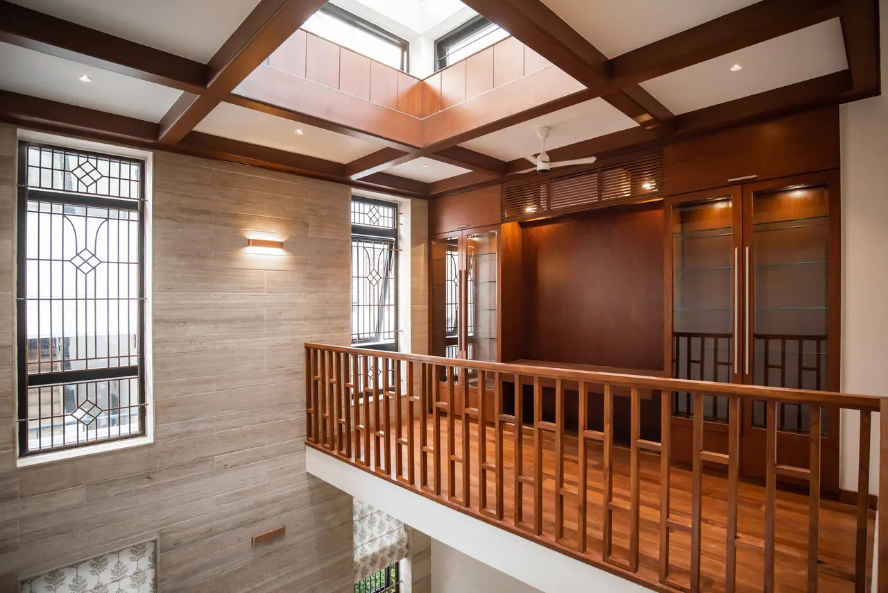 Upper landing with a coffered timber ceiling around a skylight, timber railing, stone-look wall and glass-front cabinets
