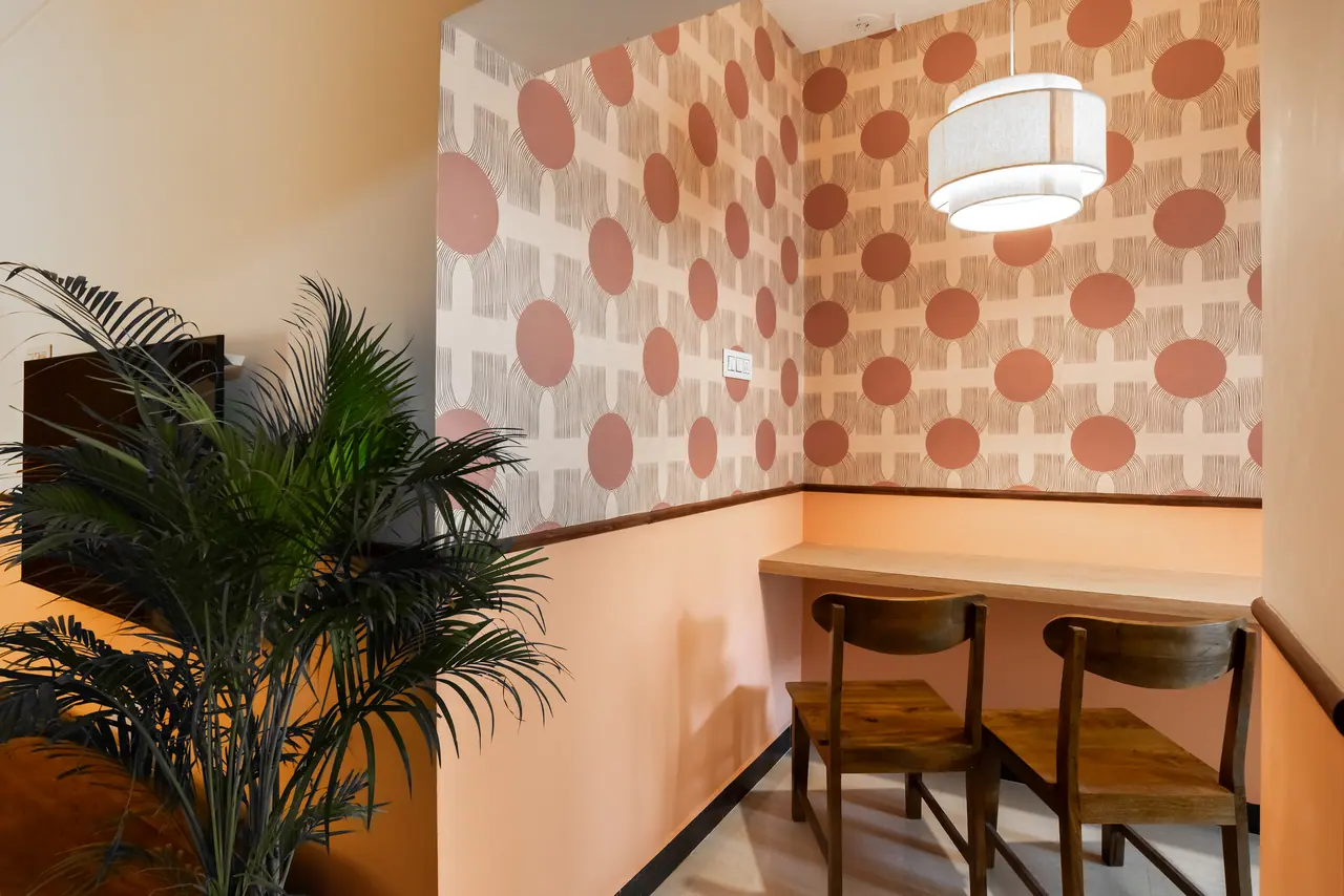 Counter nook with terracotta-circle geometric wallpaper, double drum pendant, a wall-fixed wooden counter and two chairs
