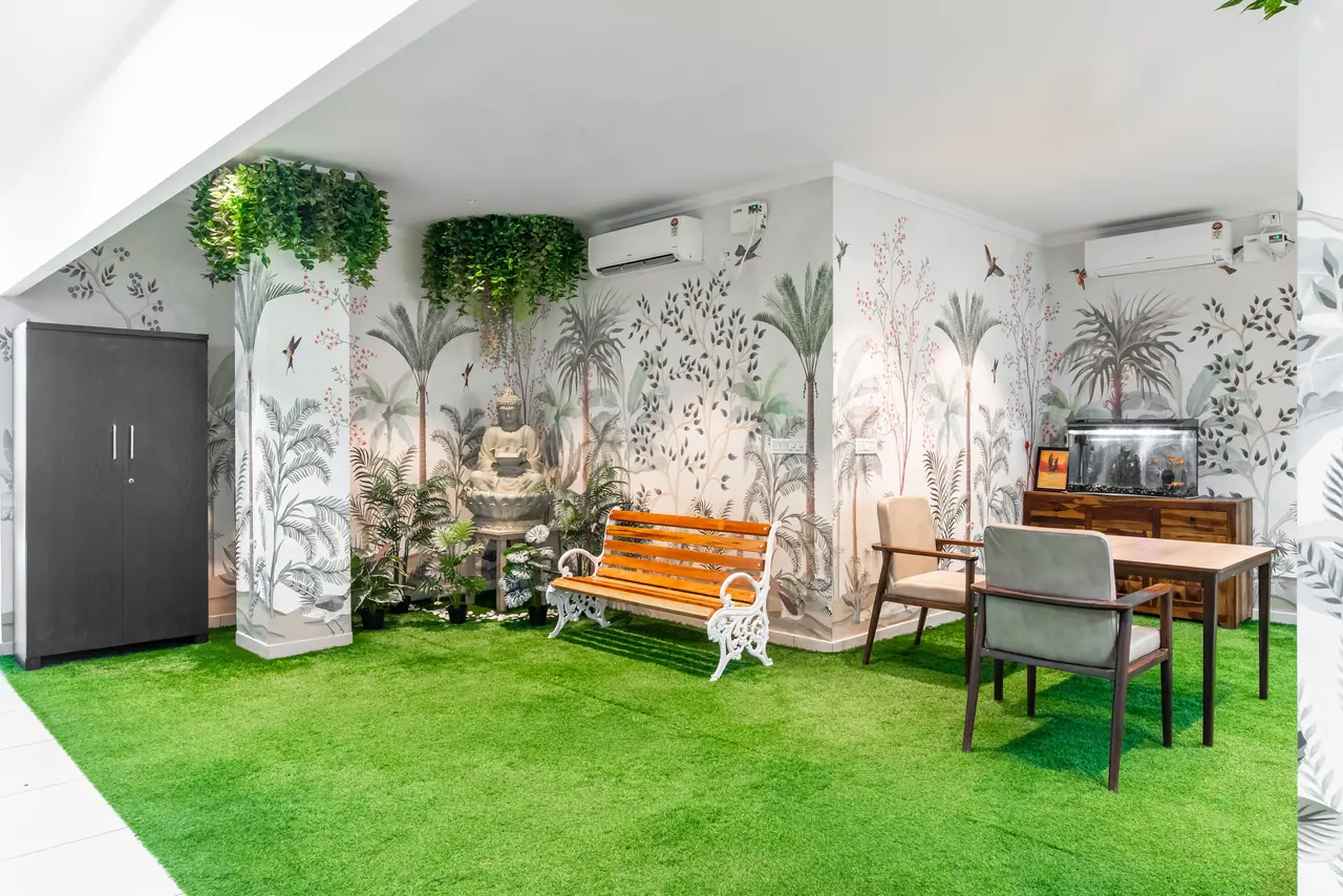 Indoor garden lounge with artificial turf, tropical bird mural, hanging greenery, slatted bench, Buddha fountain and aquarium