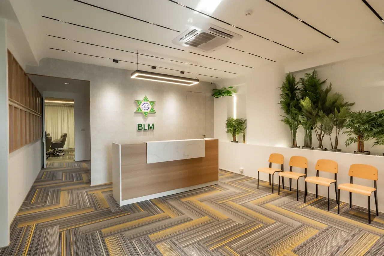 Reception with a timber and marble-look desk, herringbone carpet, a linear pendant light, oak chairs and a planter ledge