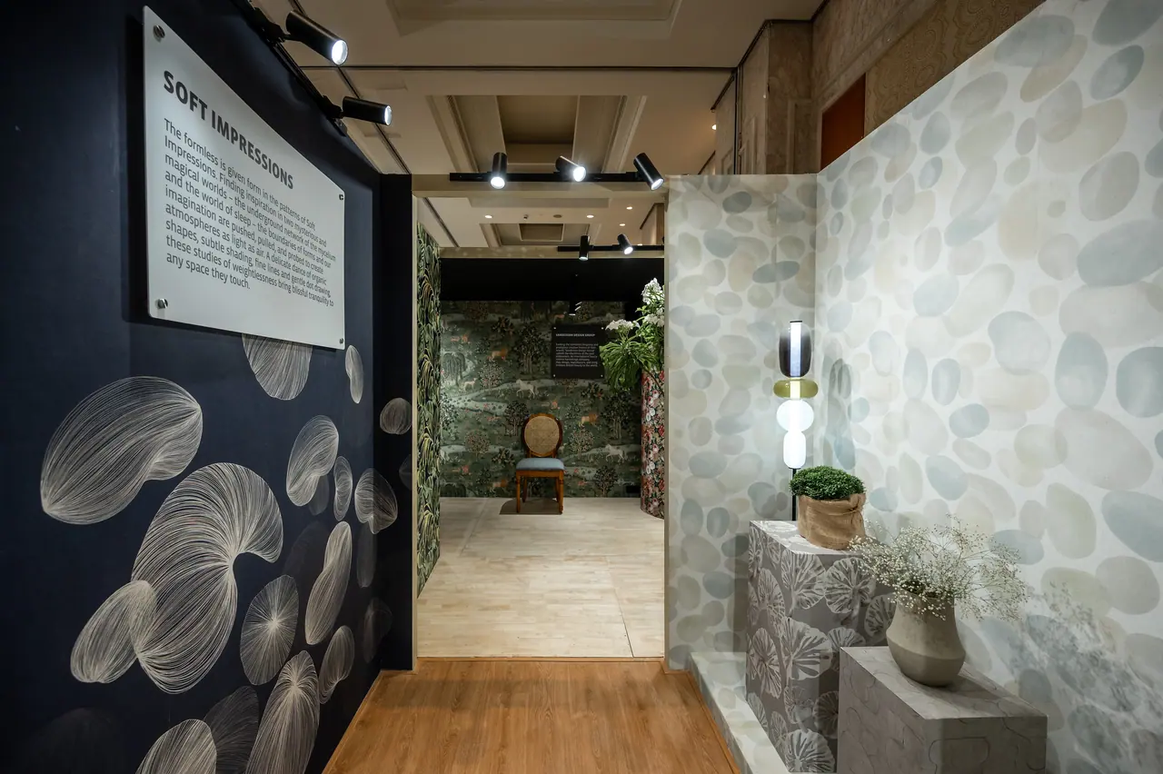 Navy wall with fine-line seed-pod motifs opposite a pebble-pattern booth, leading to a green botanical-print room and chair