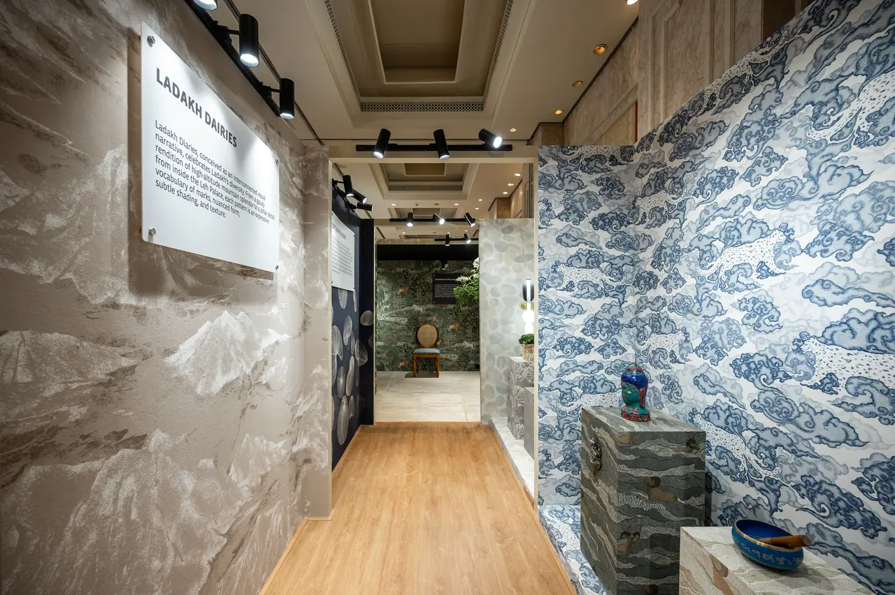 Corridor of wallcovering booths with a mountain-pattern wall, a blue cloud-pattern booth, wood floor and track spotlights